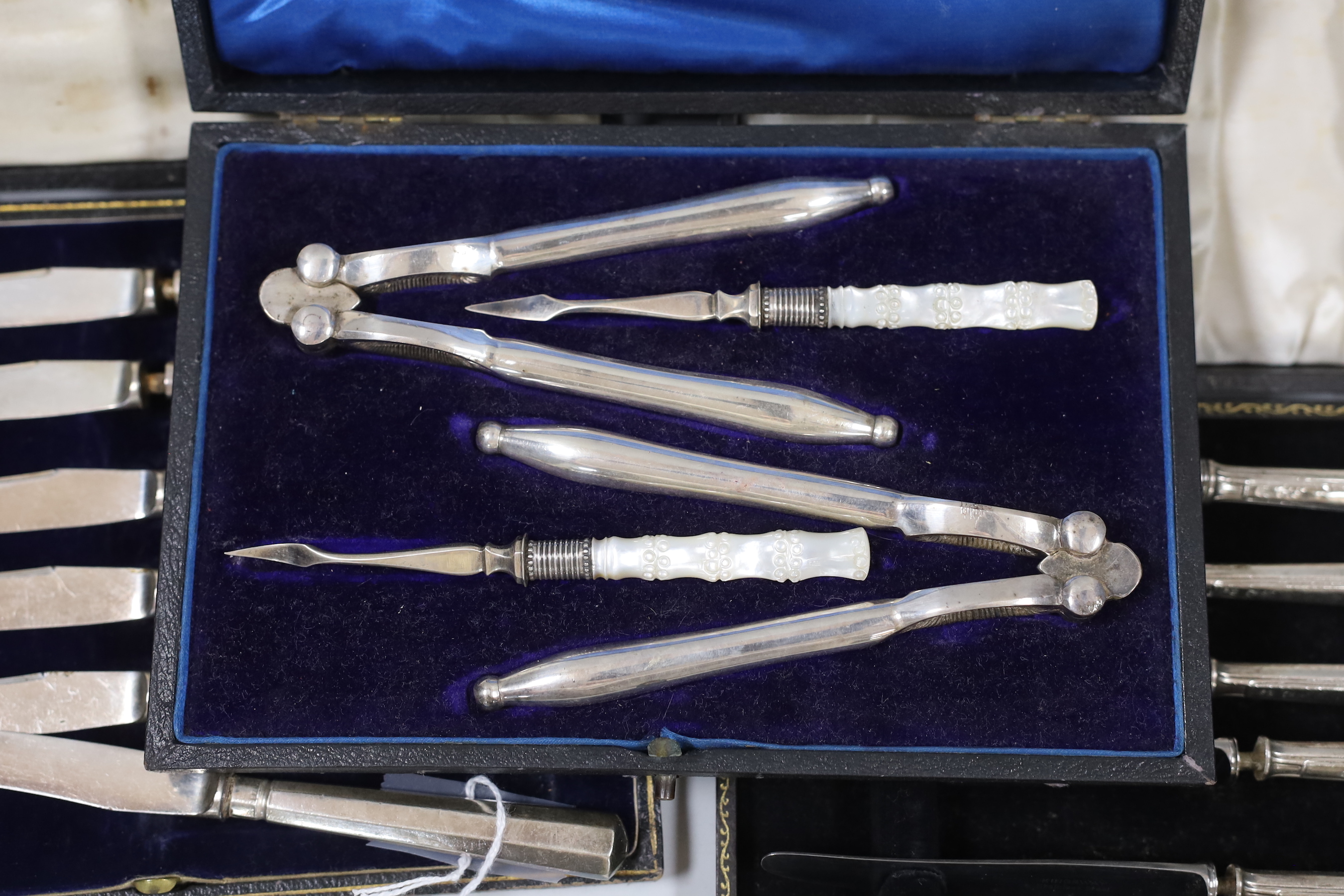 Two cased sets of six silver handled cake knives and cased plated nutcracker set.